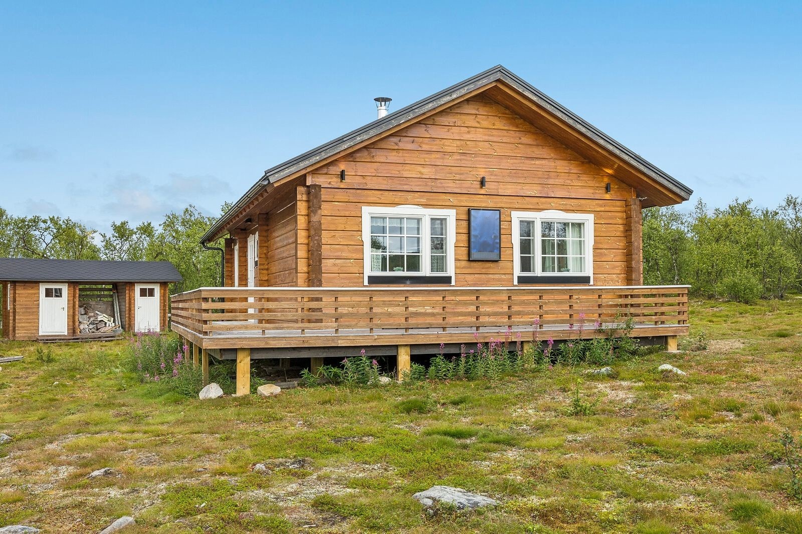 Det er en stor sørvestvendt veranda som strekker seg rundt to sider av hytta.