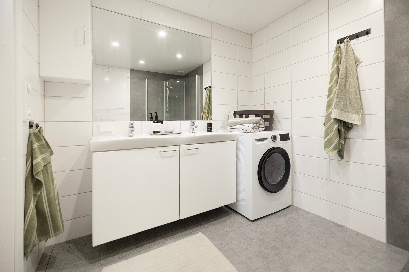 Pent og funksjonelt bad med moderne innredning, dusj og opplegg for vaskemaskin. Galleribilde