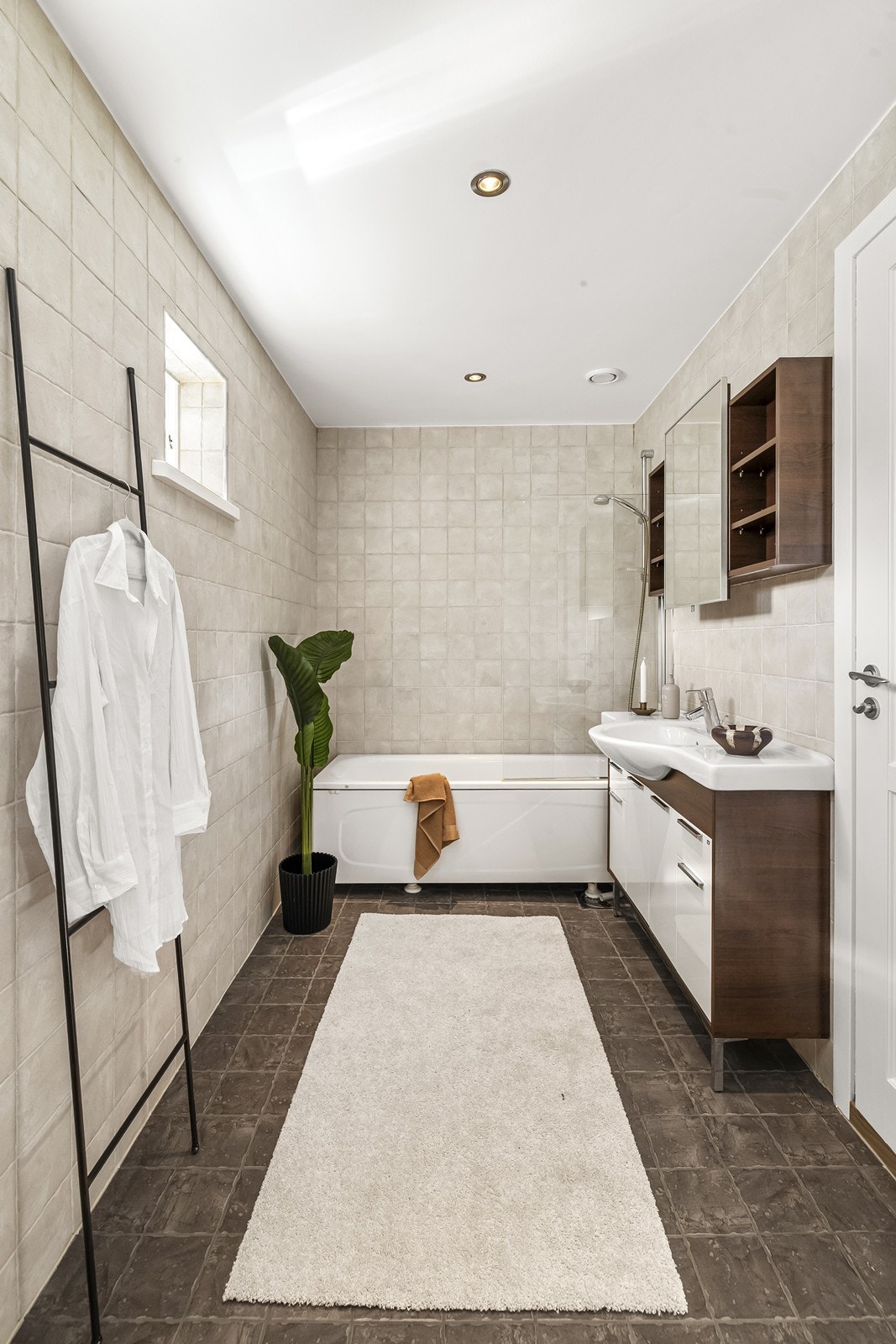 Badet har fliser på både vegger og gulv, slette overflater i himling, samt skap med glatte fronter og overskap med speilfront. Galleribilde