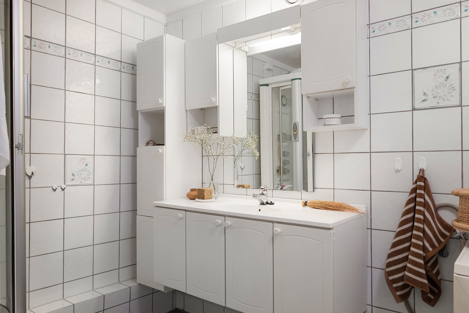 Servantinnredning med skap, høyskap og speil over sørger for gode oppbevaringsmuligheter på badet. Galleribilde