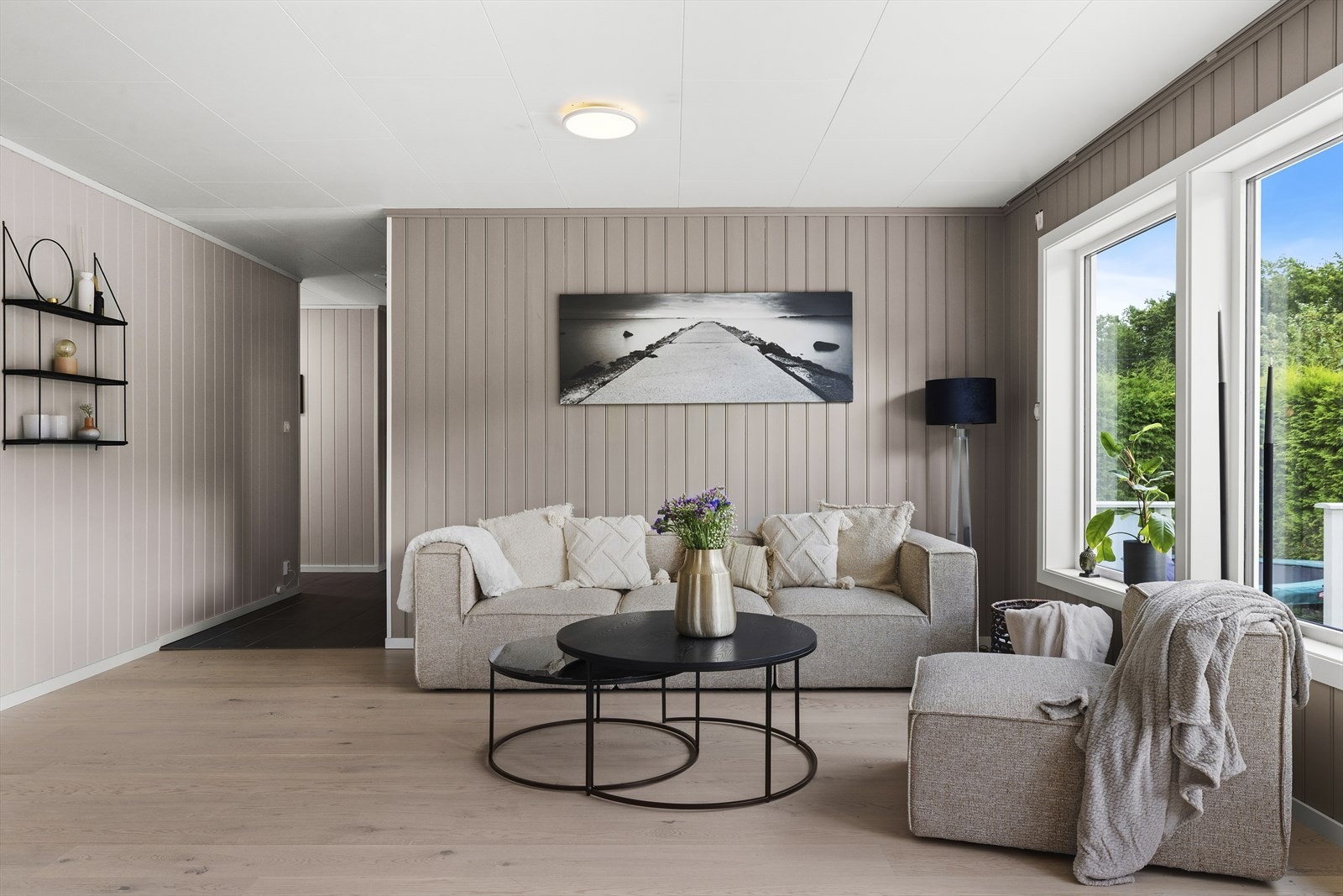 Hovedetasjens hjerte er den meget romslige og lyse stuen. Veggene er kledd med panel i en moderne gråbeige farge som harmonerer sømløst med gulvet. Galleribilde