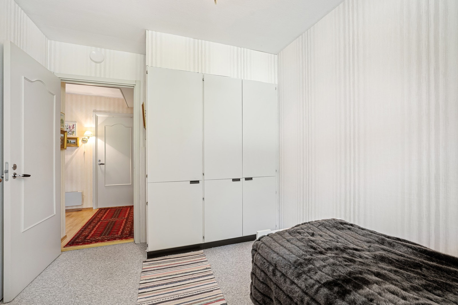 Lyst soverom med klesoppbevaring i garderobeskap. Galleribilde