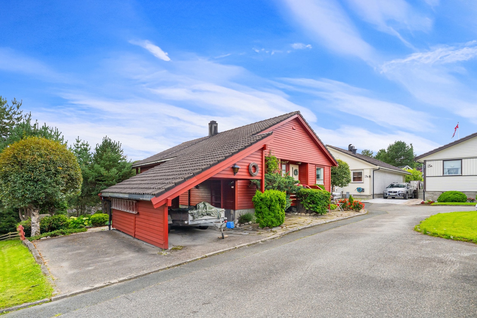 Asfaltert og steinlagt gårdsplass med parkeringsplass i carport samt oppstillingsplass. Galleribilde
