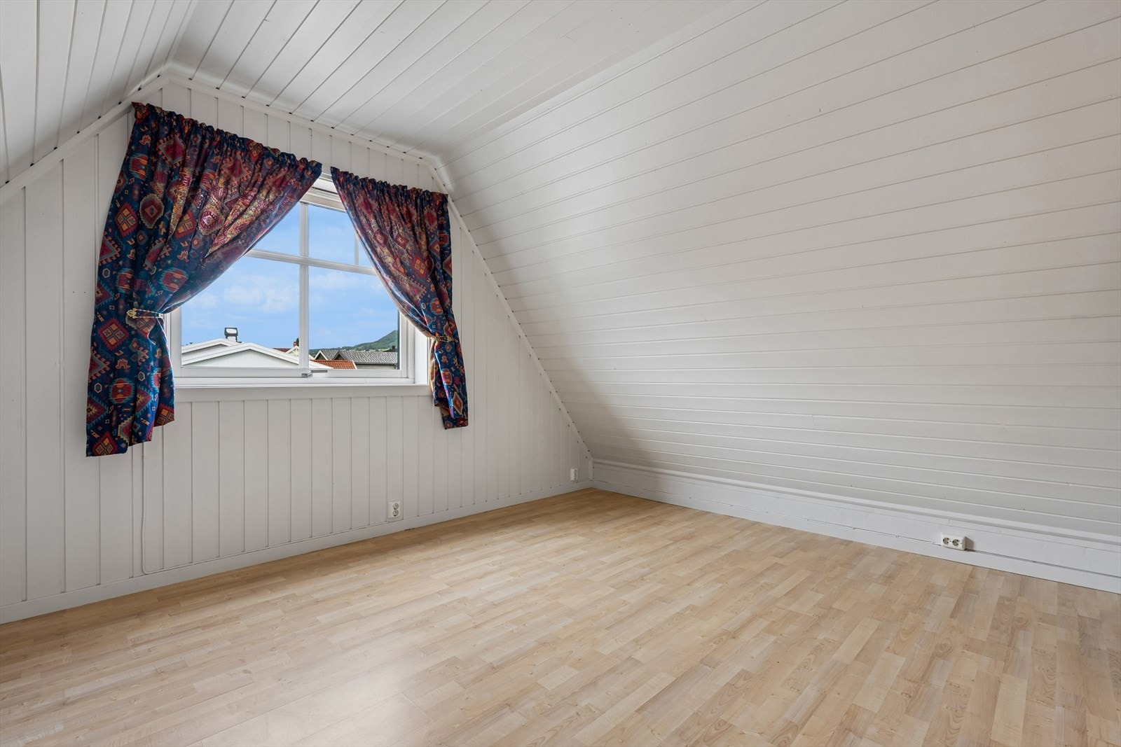 Lyst soverom i loftsetasjen med malt panel på vegger og i tak. Galleribilde