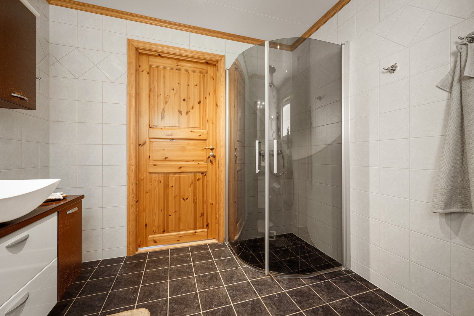 Badet er innredet med servant, vegghengt toalett, dusj og varmekabler i gulvet Galleribilde