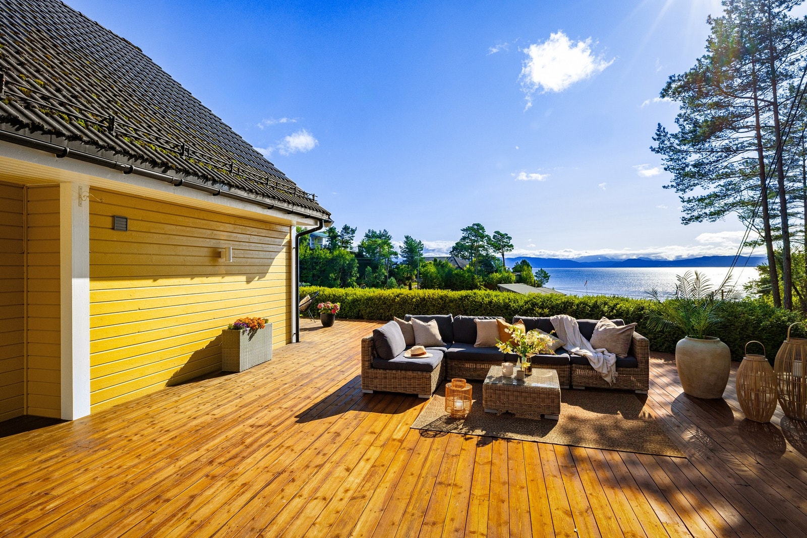 Tomten er opparbeidet med asfaltert tun til garasje, stor terrasse, kantmur, bed, beplantning og noe naturtomt. Galleribilde