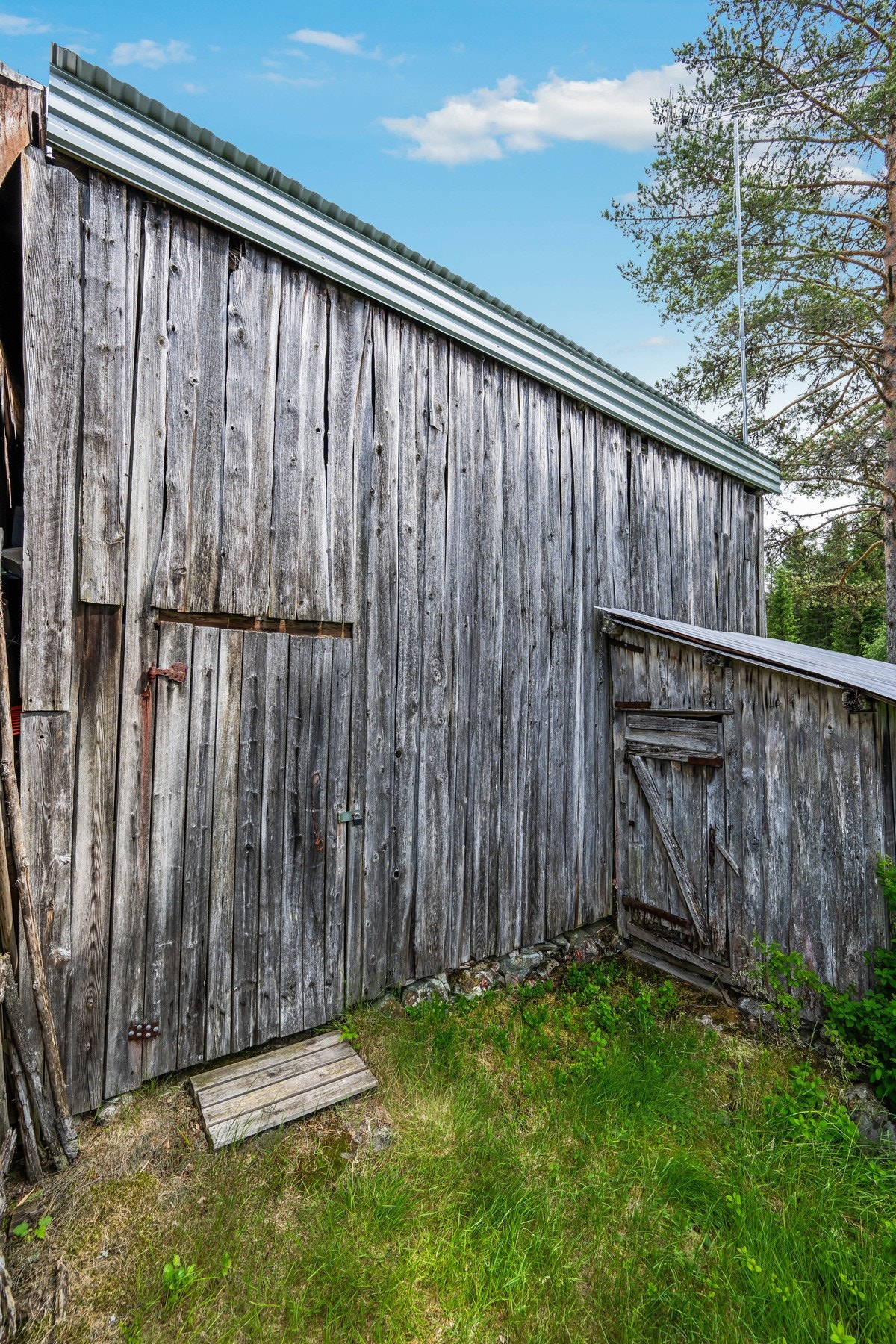 Et sjarmerende uthus med værbitt trekledning - en naturlig og karakterfull del av det tradisjonelle tunet. Galleribilde
