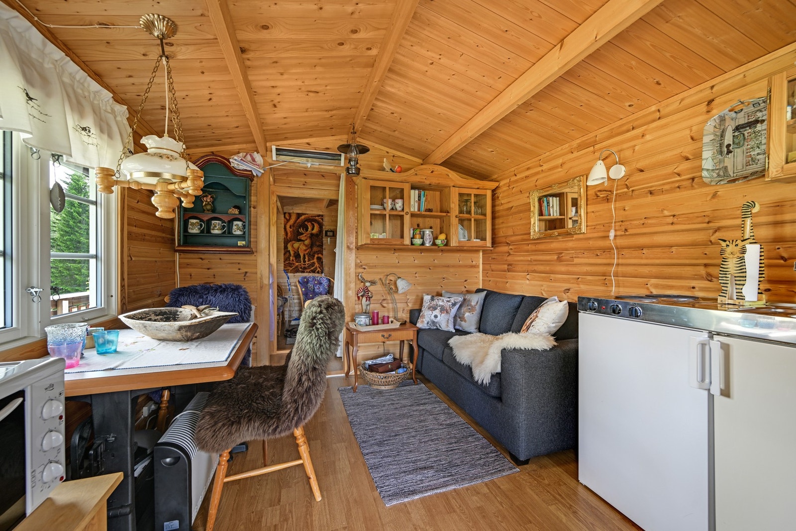 Stue og kjøkken er samlet i et hyggelig allrom med gjennomgående trepanel og en lun, tradisjonell atmosfære. Galleribilde