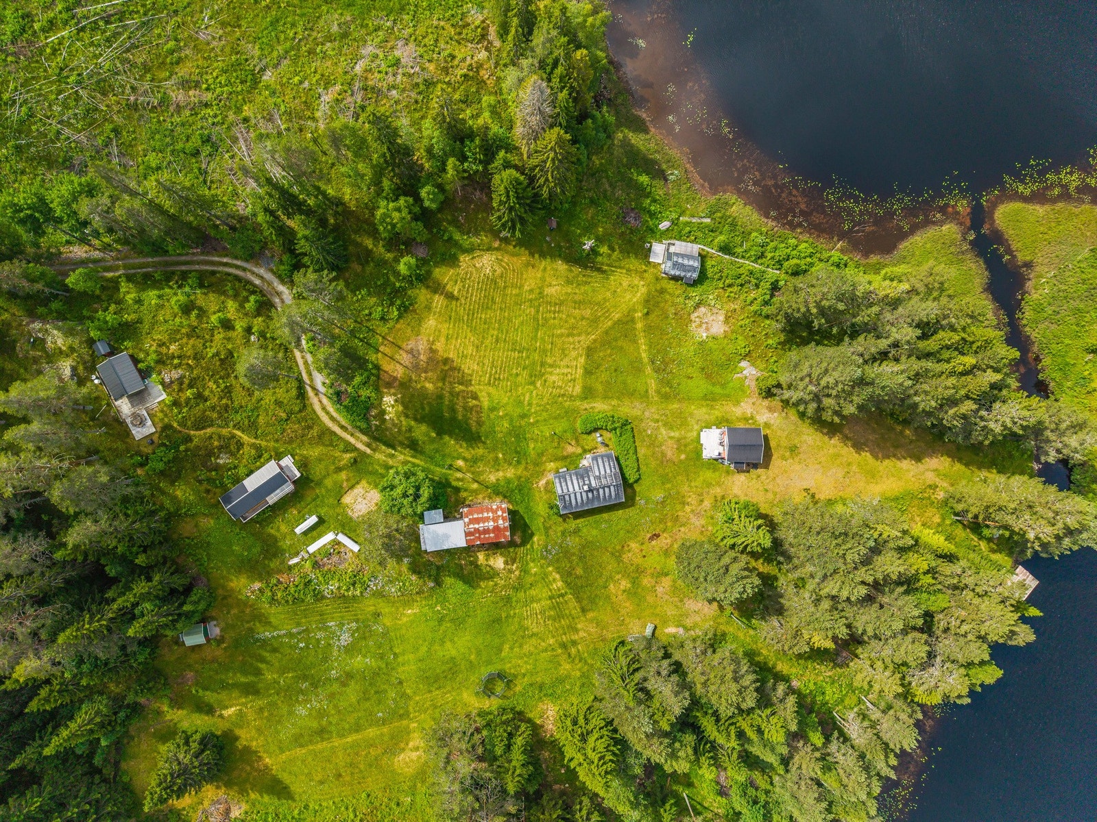 Sett ovenfra kommer eiendommens helt spesielle beliggenhet tydelig frem - et stort og åpent tun omgitt av skog og vann. Galleribilde