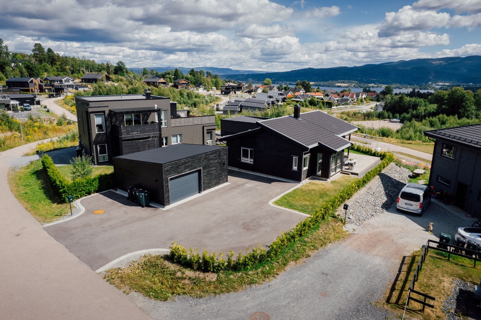 Oversiktsbilde av bolig, garasje og stor opparbeidet gårdsplass. Galleribilde