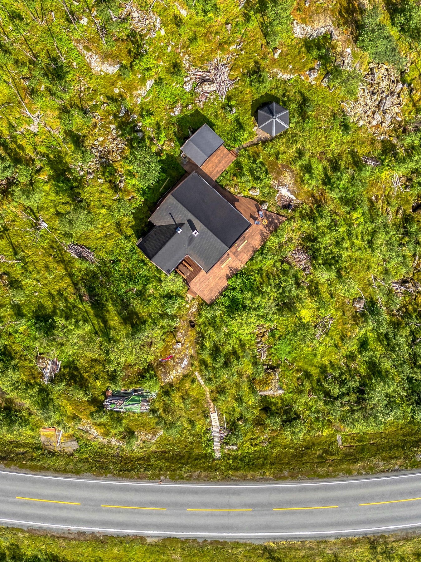 Eiendommen sett fra oven, med hytte, uthus og grillhytte. Galleribilde