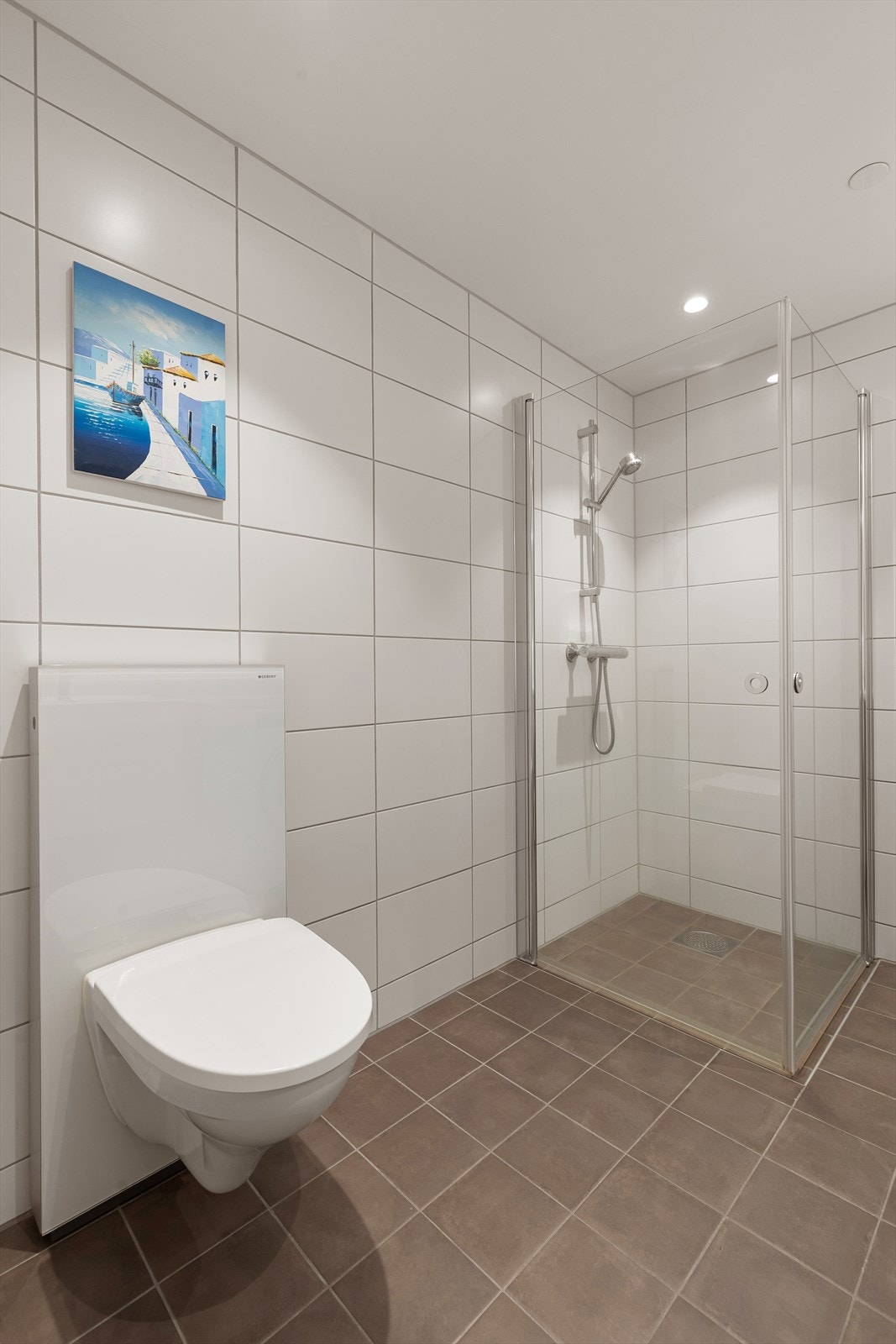 Badet er utstyrt med heldekkende servant med underskap, speil, toalett og dusjkabinett Galleribilde