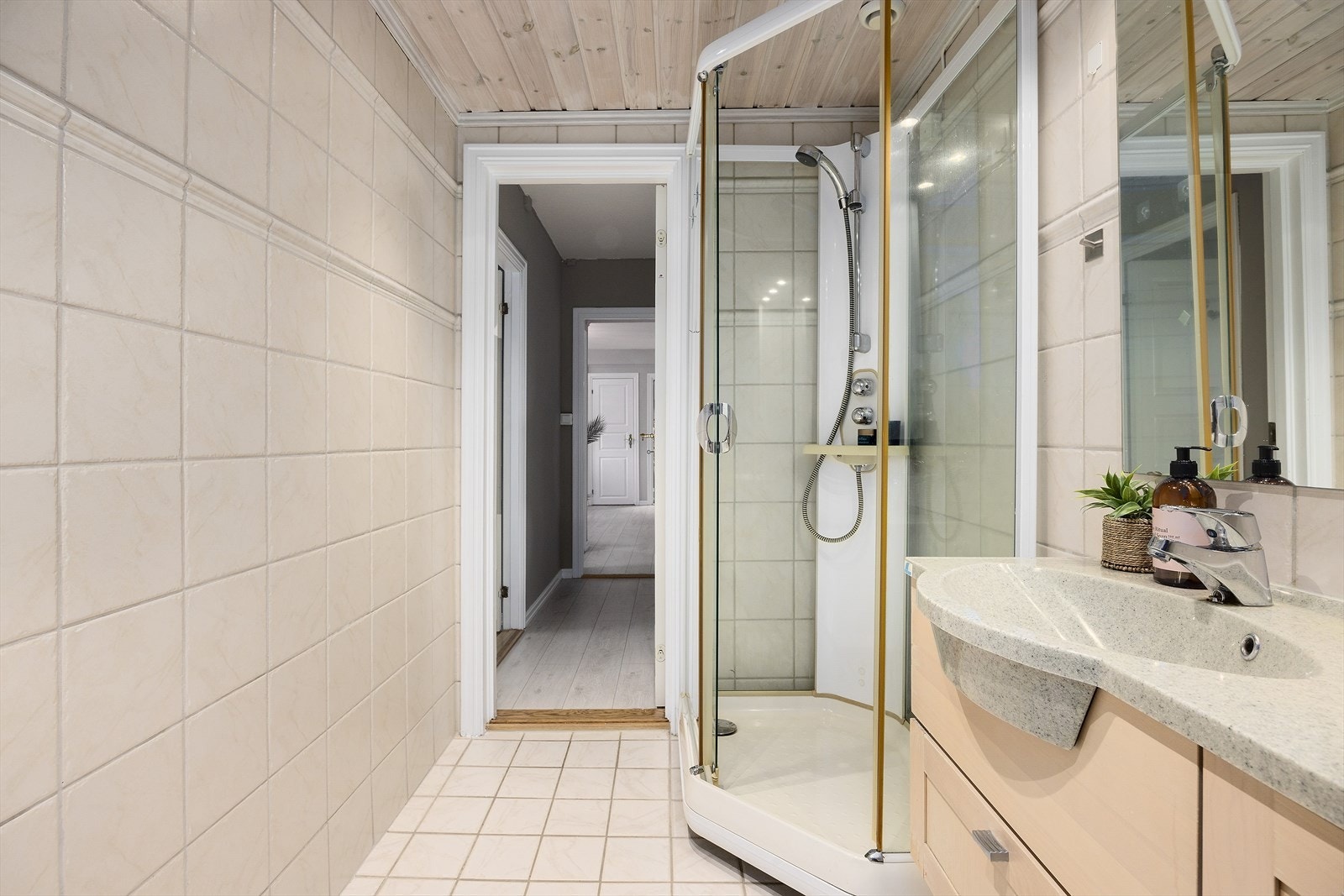 Badet er innredet med servant med tilhørende skap, armatur fra Oras, veggskap med glassfront, dusjkabinett og gulvstående toalett. Det er mekanisk avtrekk. Galleribilde
