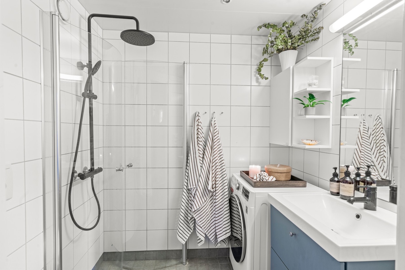 Lyst og praktisk bad med flislagte overflater, dusjplass, vegghengt WC og servantinnredning. Badet har gulvvarme og downlights med dimmer. Galleribilde