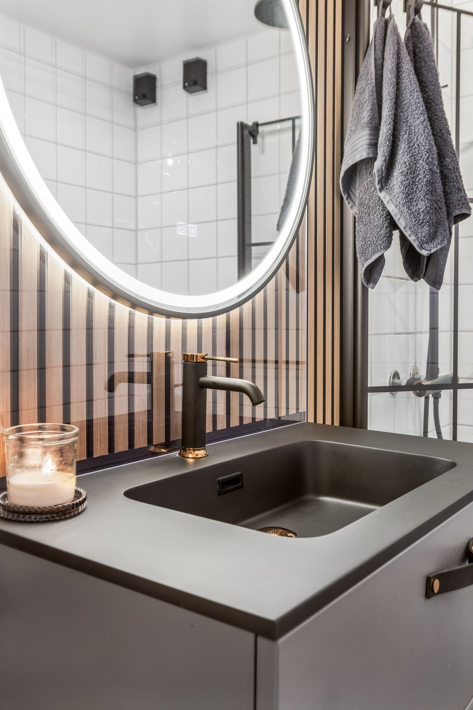 Badet er originalt fra 2001, men har fått et tydelig visuelt løft med oppdatert inventar og gjennomgående materialvalg. Spileveggen henter opp igjen uttrykket fra stue og soverom, mens nytt lysspeil og sort baderomsmøbel med kobberdetaljer skaper en moder Galleribilde