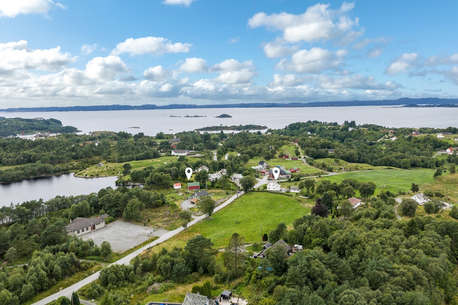 Rolig og landlig bygdemiljø omgitt av åpne jordbruksarealer, skog og vann. Galleribilde