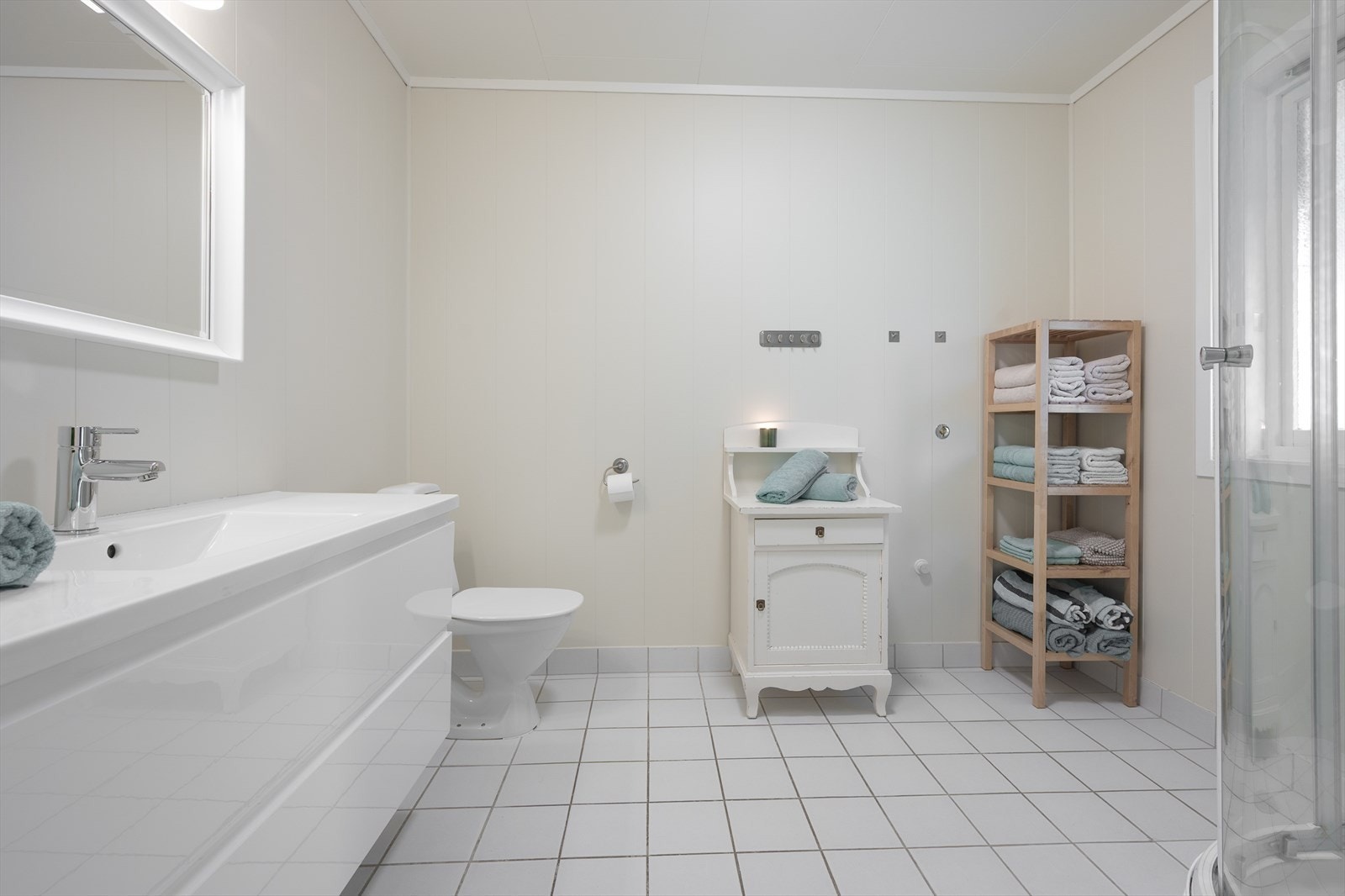 Romslig baderom med servant i møbel og toalett. Galleribilde