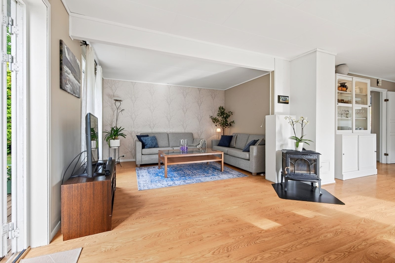 Stuen er i vinkel, med god plass til sofagruppe og en sentralt plassert vedovn. Galleribilde