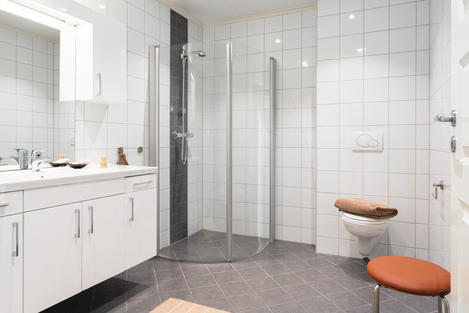 Badet er innredet med to nedfelte servanter, veggmontert toalett og et innbydende dusjhjørne med glassvegger. Galleribilde