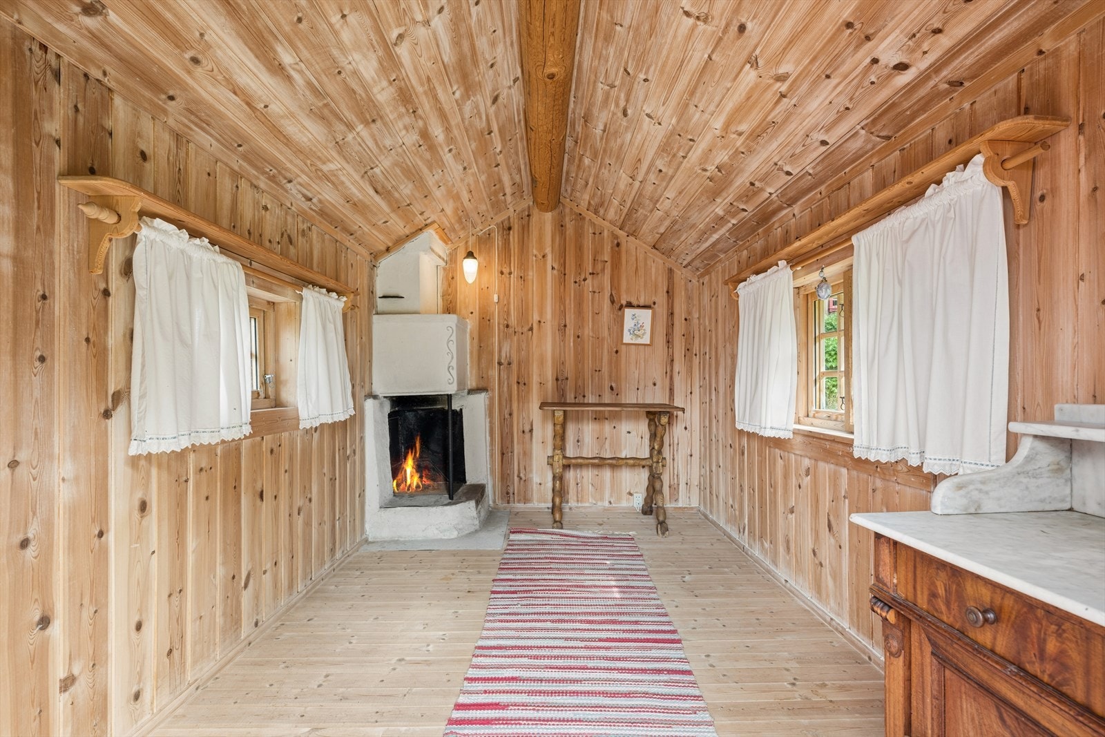 Det ene stabburet er innredet som et rom med åpen peis. Galleribilde
