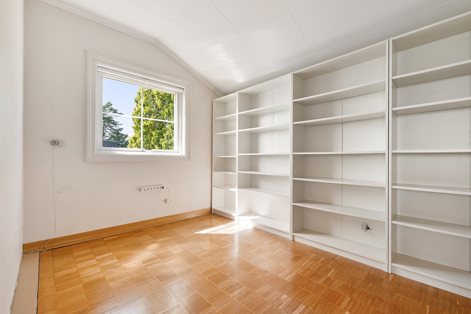 Etasjen har ett soverom med skråtak langs den ene veggen. En vegg med innebygde hyller gir gode oppbevaringsmuligheter, og vinduet vender mot hagen. Galleribilde