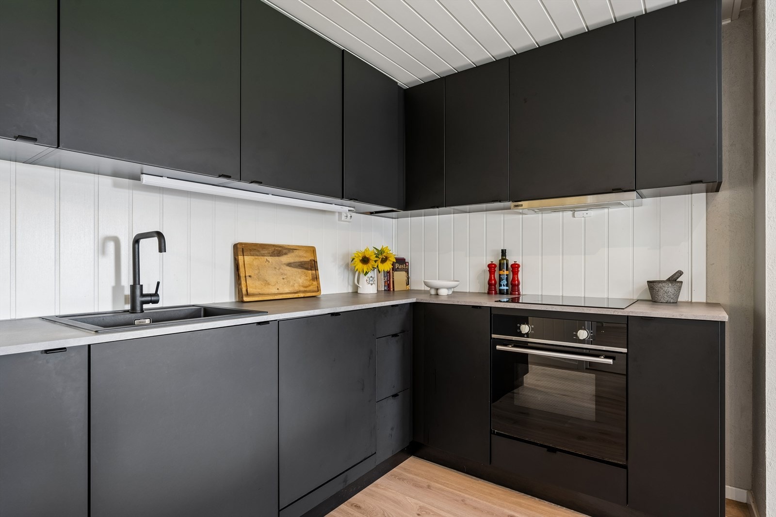 Kjøkkeninnredning med glatte, mørke fronter og benkeplate i laminat. Galleribilde