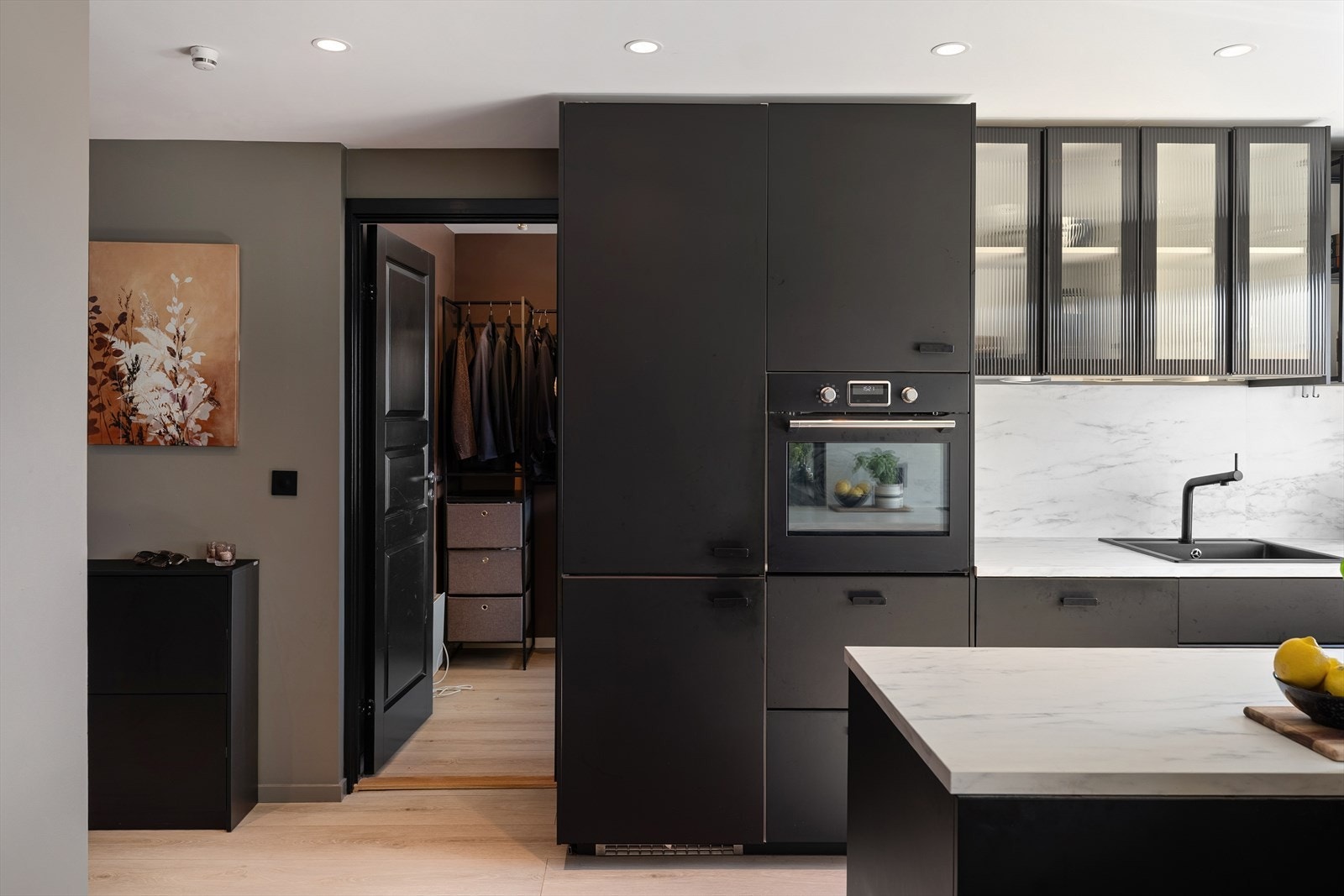 Pent og moderne kjøkken fra 2019 med malte, sorte, glatte fronter og glassdører. Kjøkkenet har laminat benkeplate med nedfelt vaskekum og platetopp. Galleribilde