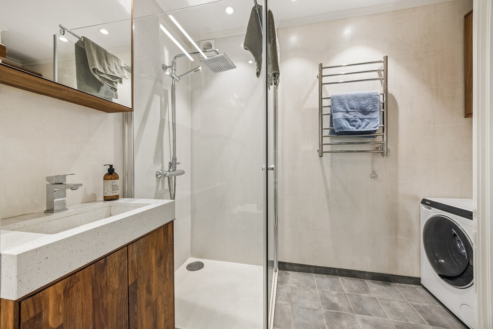 Badet er innredet med flislagt gulv med behagelige varmekabler, våtromsplater på veggene og malt himling, noe som gir et praktisk og vedlikeholdsvennlig uttrykk. Galleribilde