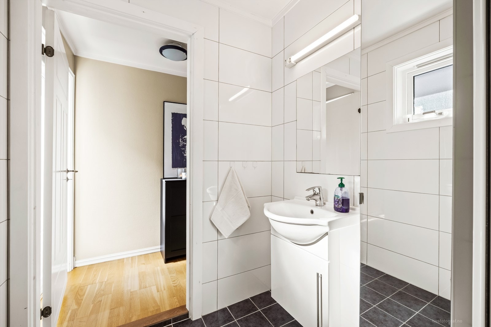 Badet i 1.etasje har hvite fliser på veggene, malt himling og flislagt gulv med elektriske varmekabler som bidrar til god komfort. Galleribilde