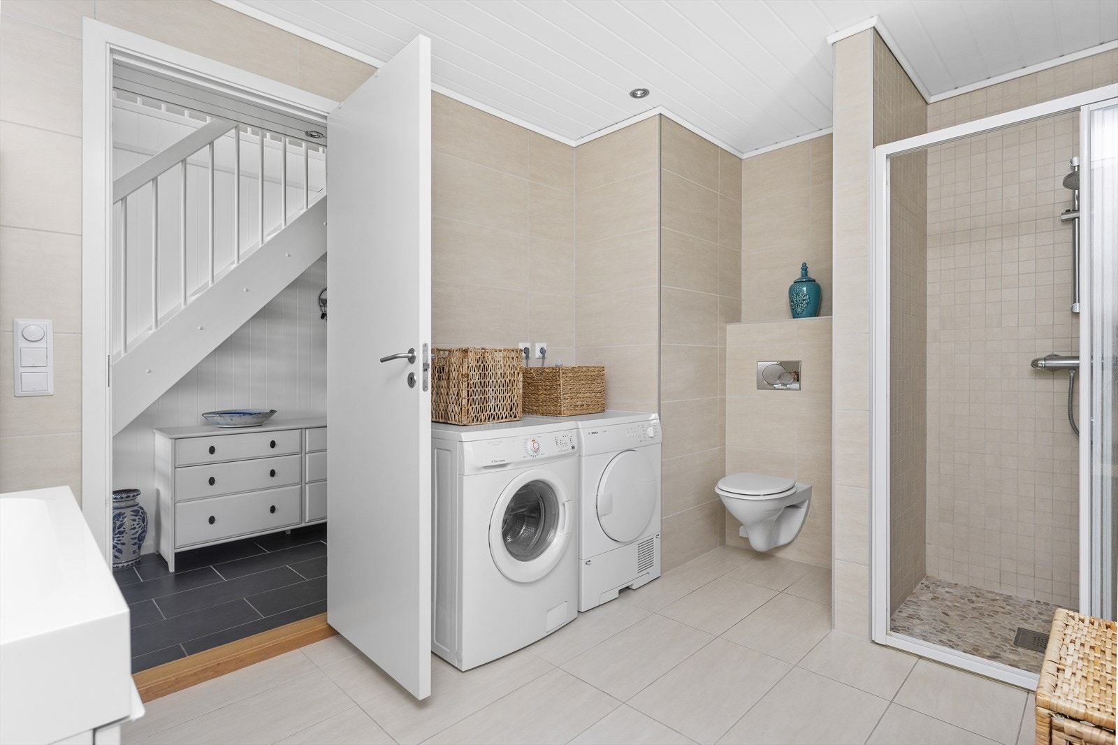 Badet er utstyrt med vegghengt toalett, dusjhjørne og opplegg for vaskemaskin. Galleribilde