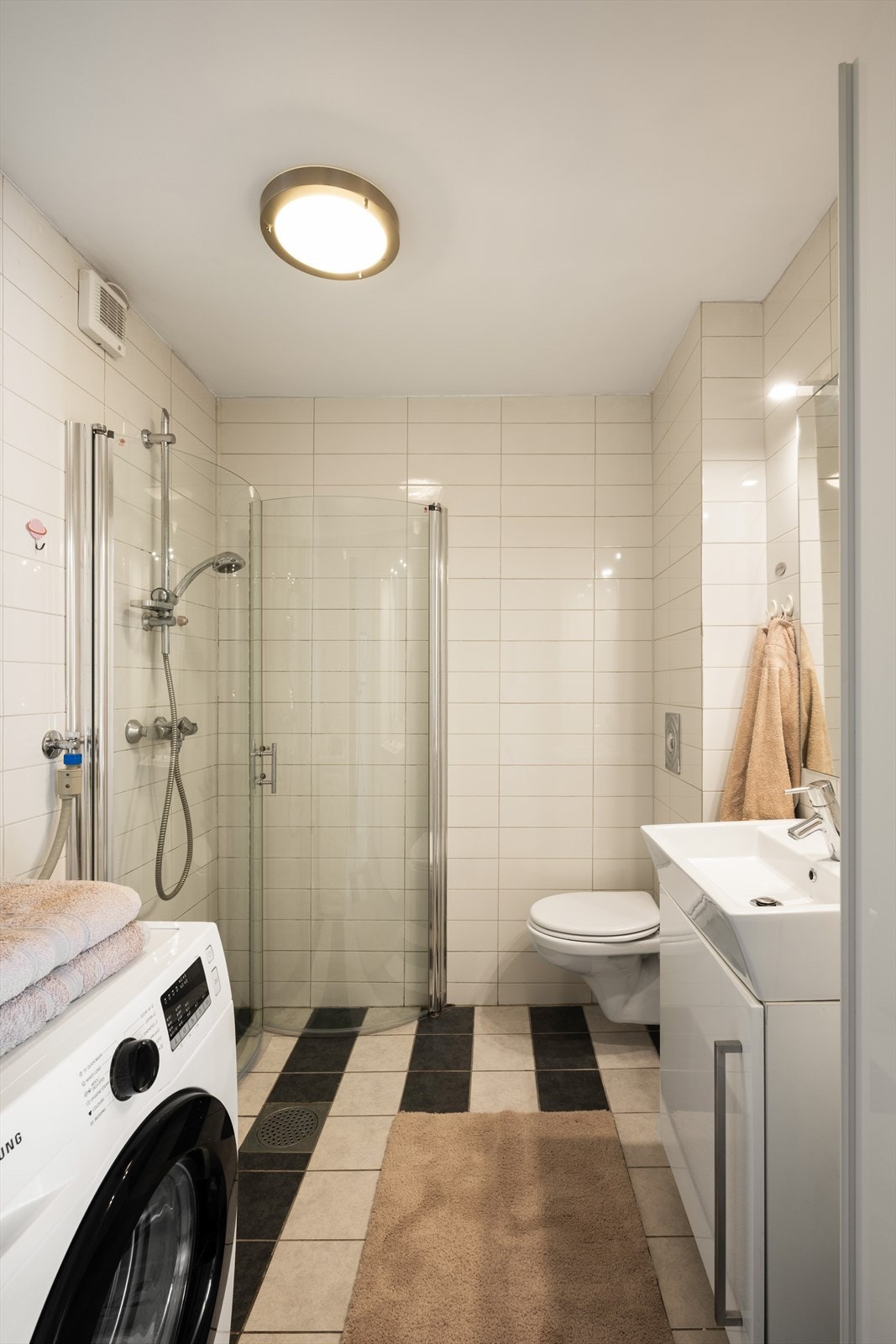 Badet er pent helfliset og inneholder servant i møblement, speil m/belysning, dusjhjørne og vegghengt toalett. Galleribilde