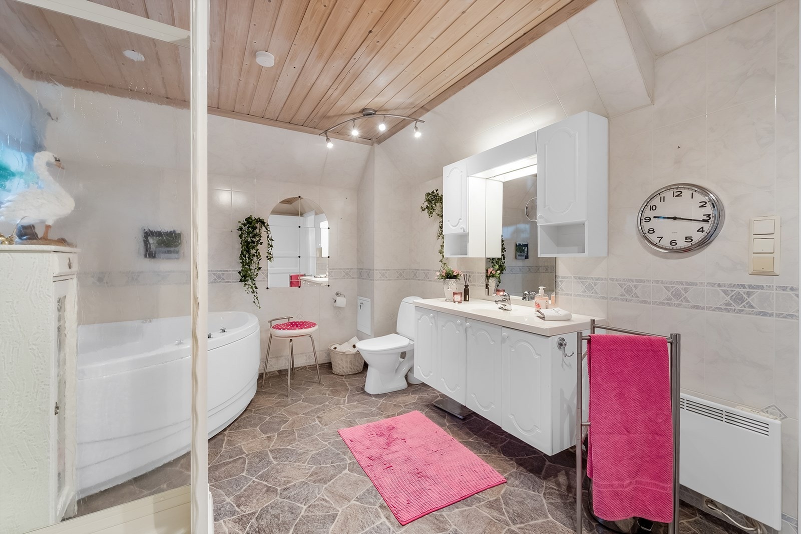 Stort bad med belegg på gulv og baderomsplater på vegg. Innredet med badekar, dusj, toalett og baderomsinnredning Galleribilde