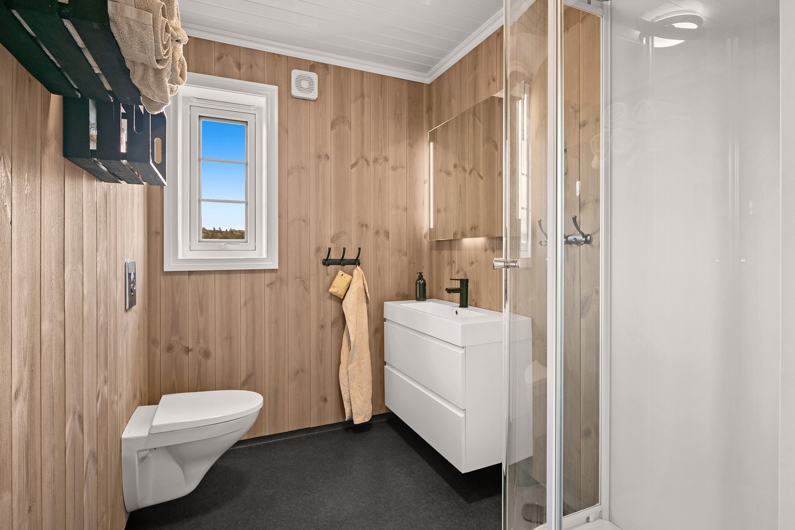 Badet er innredet med dusjkabinett, servant og WC. Galleribilde