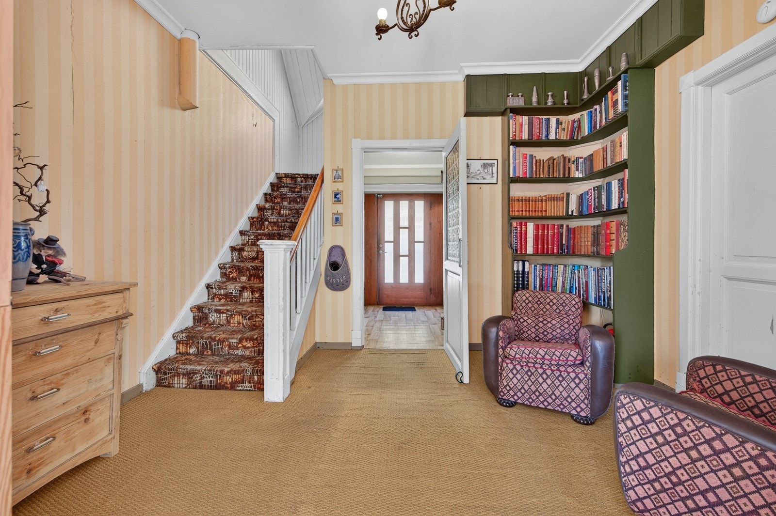 Hall med plassbygd bokhylle og original trapp til loft Galleribilde