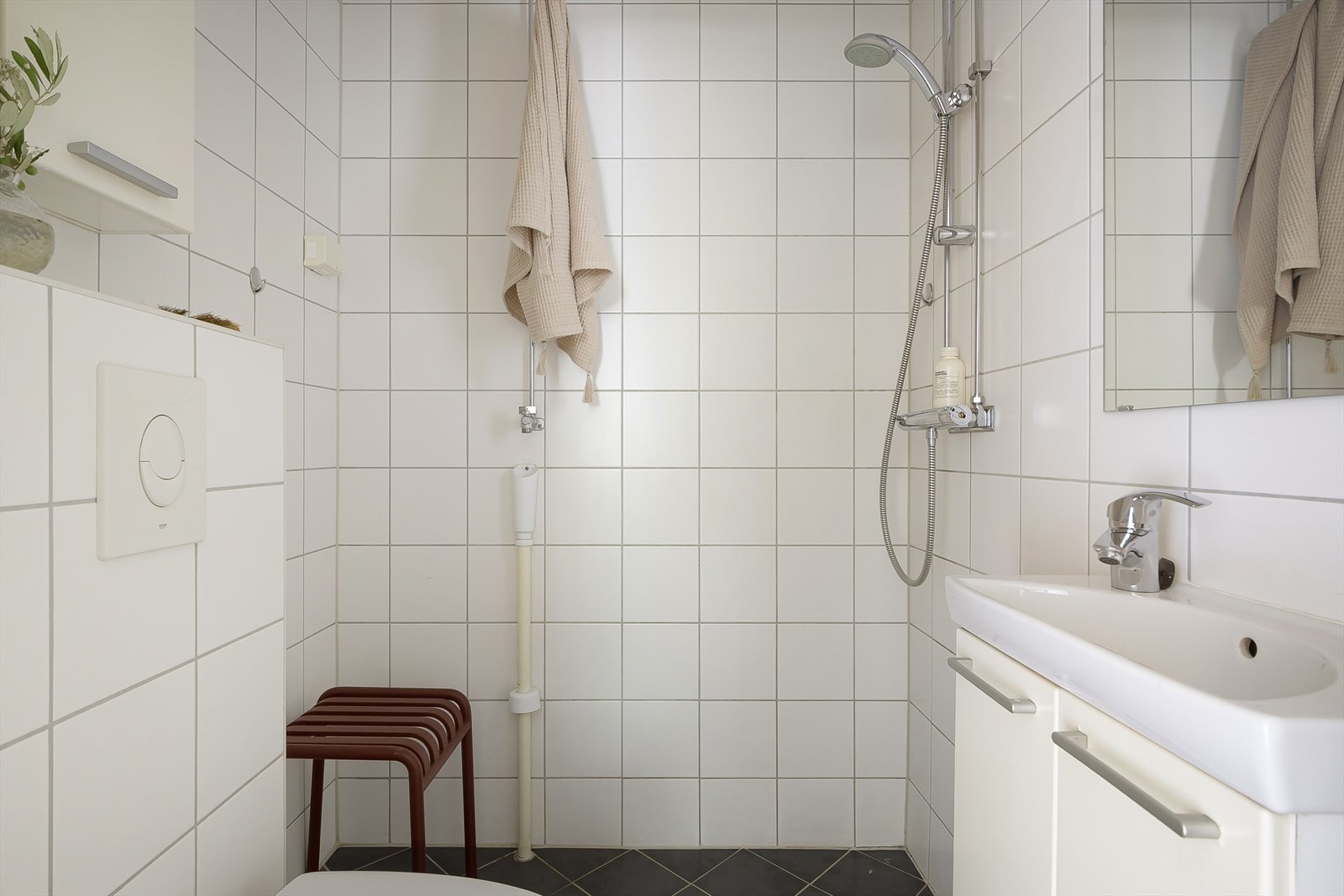 Badet er utstyrt med åpen dusj, servant, vegghengt klosett med innebygd sisterne og opplegg for vaskemaskin og tørketrommel.. Galleribilde