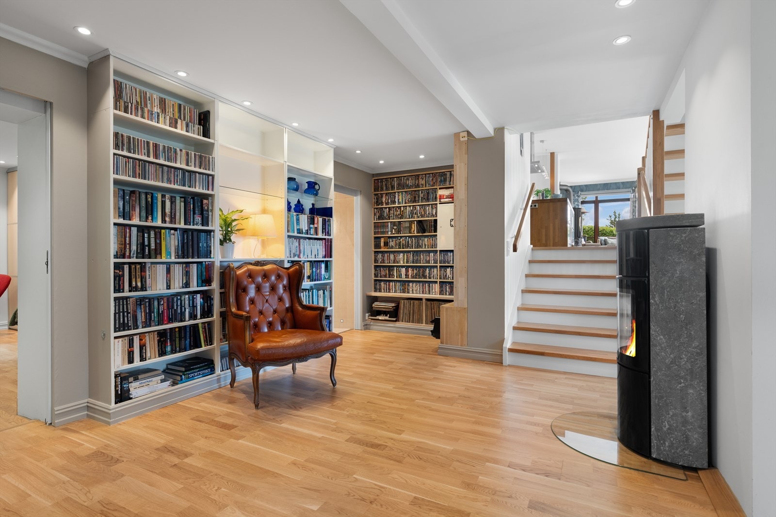 Flott peisestue/bibliotek med praktiske hyller, moderne peisovn og plass for sittemøblement Galleribilde