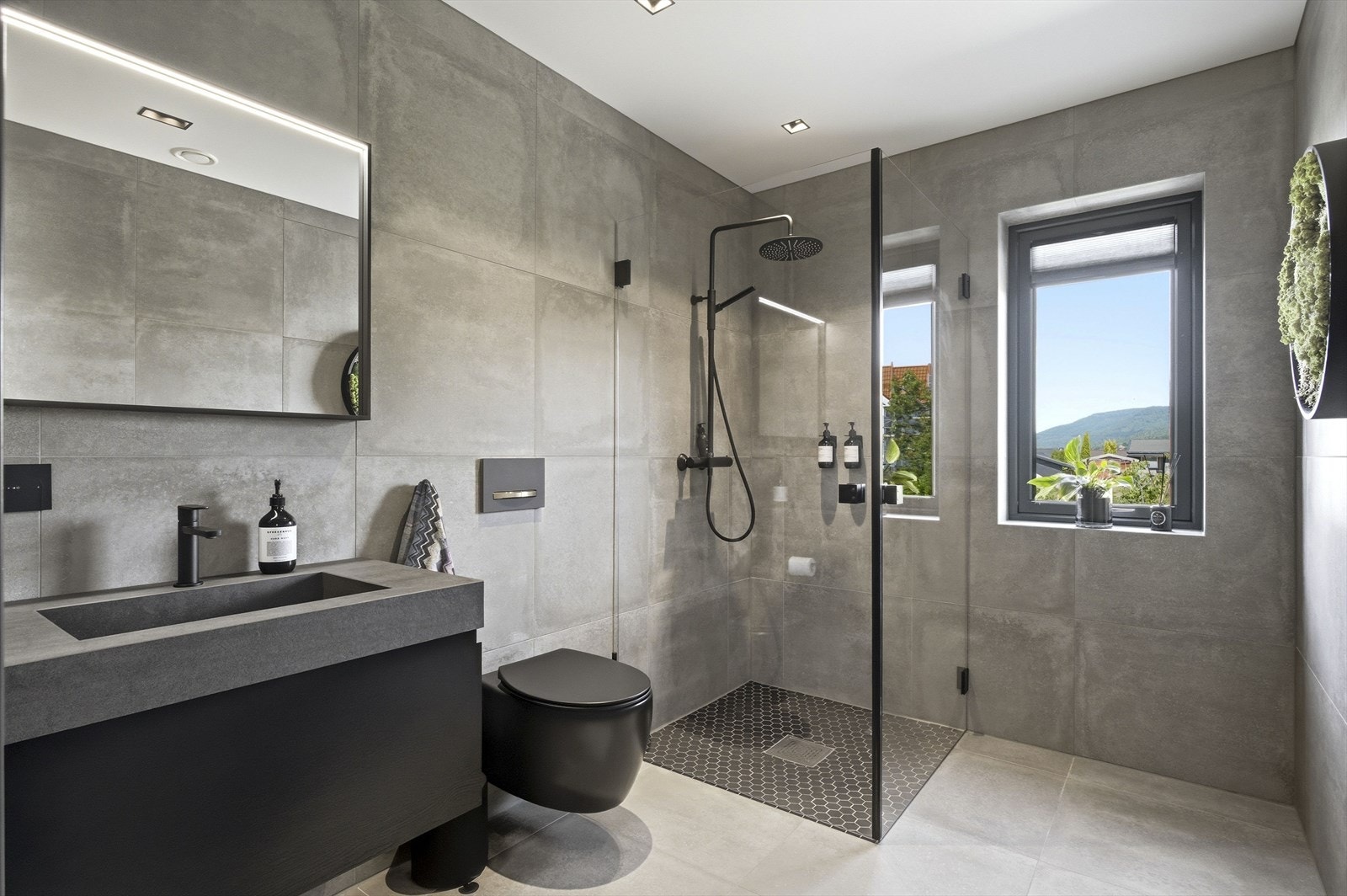 Badet har flislagt gulv med gulvvarme og veggmontert toalett. Galleribilde