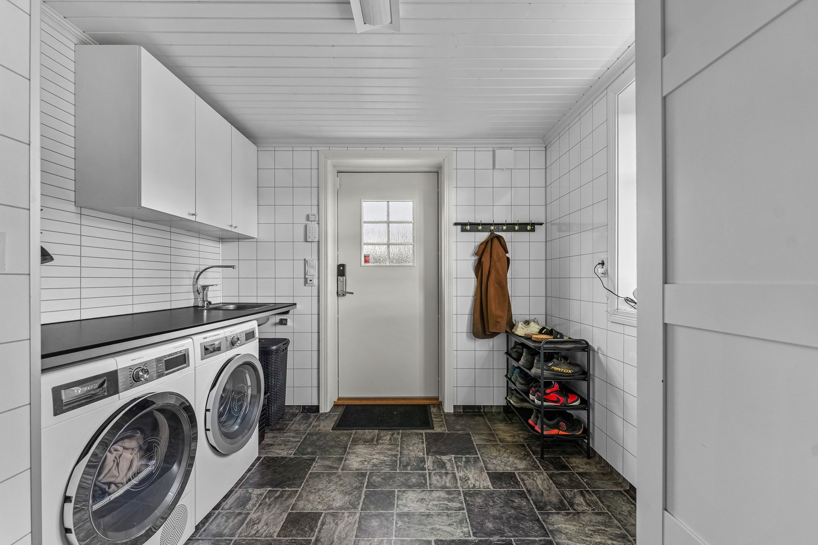 Vaskerommet er en skikkelig hverdagsfordel, med vaskemaskin og tørketrommel, utslagsvask, skapplass og egen sideinngang - praktisk for både små og store familier. Galleribilde