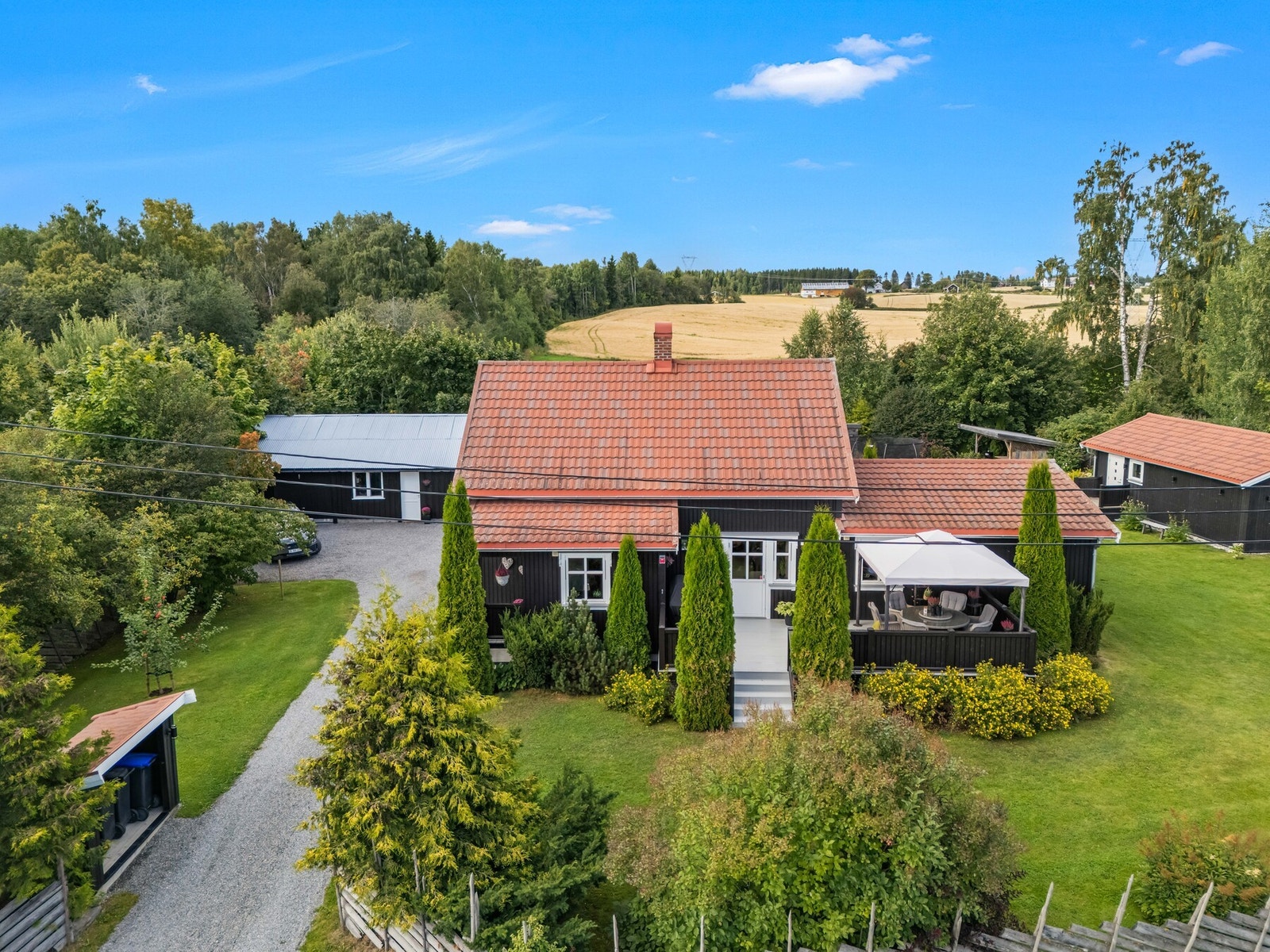 Fra luften får man virkelig inntrykk av hvor mye eiendommen har å by på - bolighus, frodig hage, terrasse, uthus og flere hyggelige soner fordelt utover tomten. Galleribilde