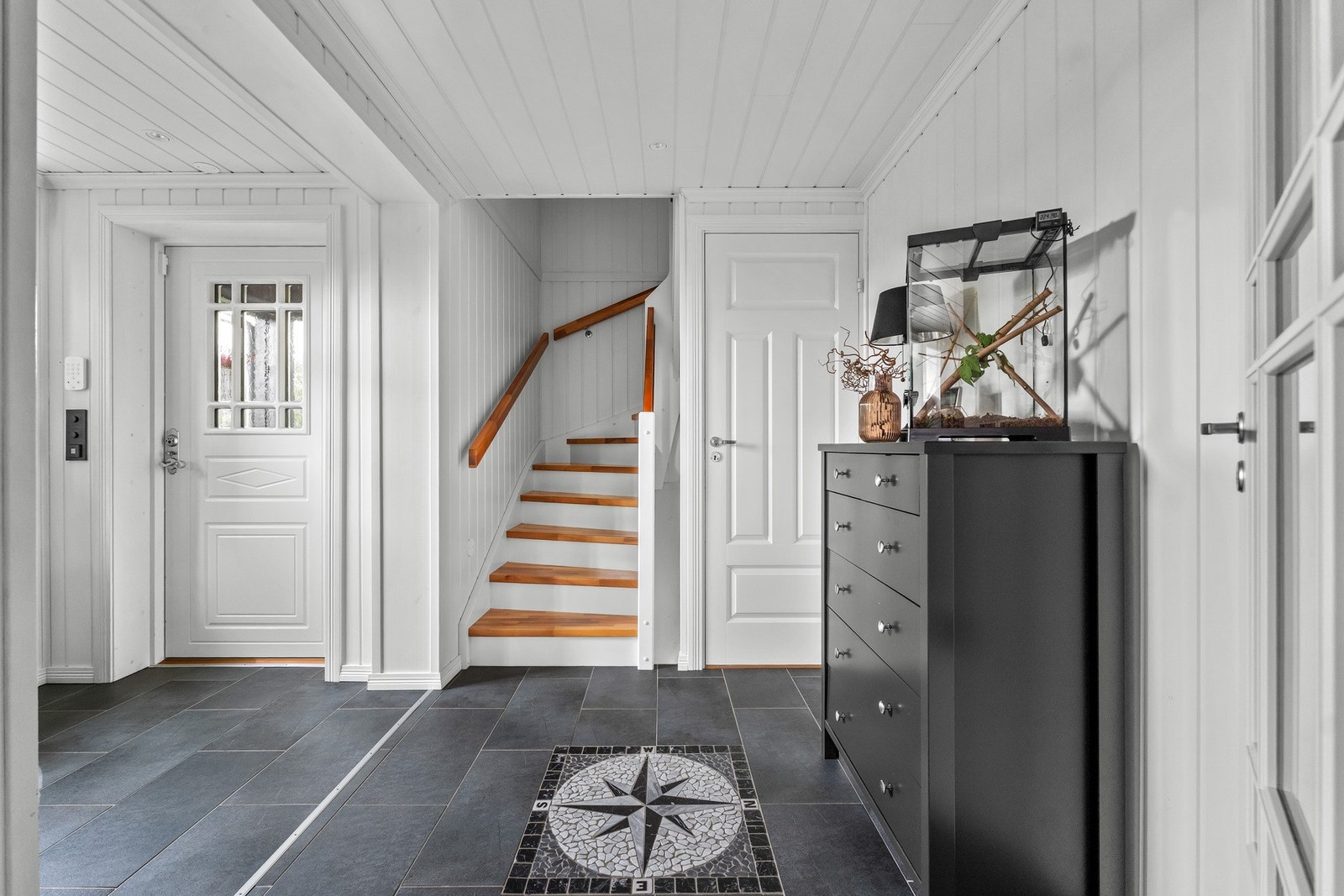 Entréen gir et lyst og hyggelig førsteinntrykk, med flislagt gulv og trappen som leder videre opp til boligens andre etasje. Galleribilde