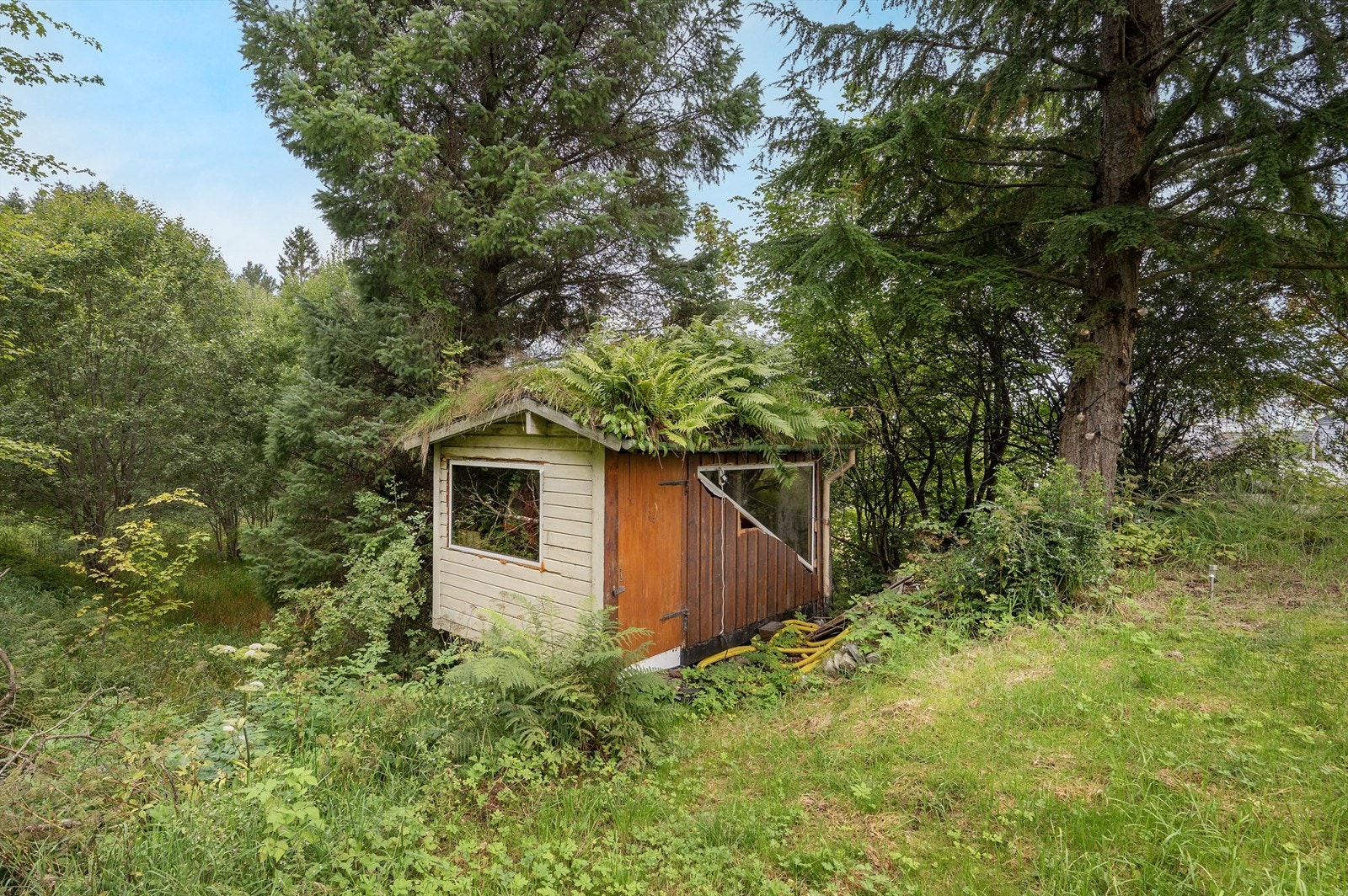 Frittstående bod med torvtak gir ekstra lagringsplass på eiendommen. Galleribilde