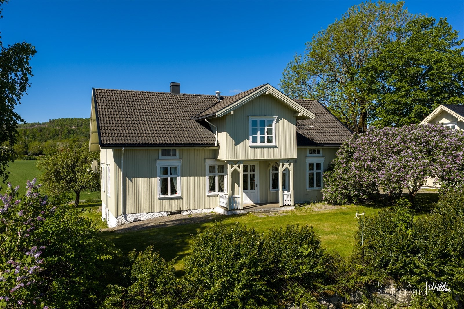 Hovedhuset med syriner i blomst, sett fra øst. Galleribilde