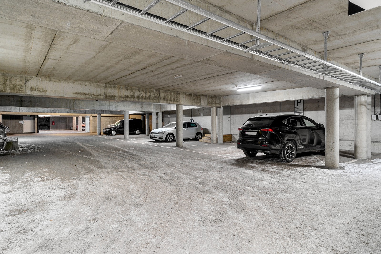 Fast parkeringsplass under tak, med elbil-lader. Borettslaget har utgang direkte til parkeringsanlegget.