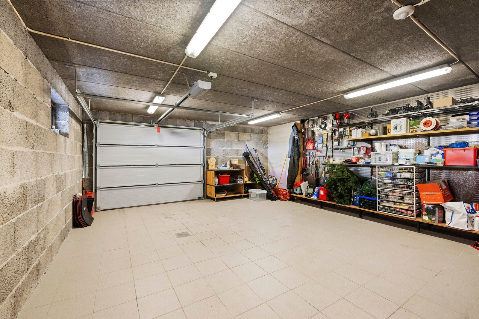 Funksjonell garasje med enkel adkomst via leddport og god kapasitet for oppbevaring av bil, ski og annet utstyr. Galleribilde