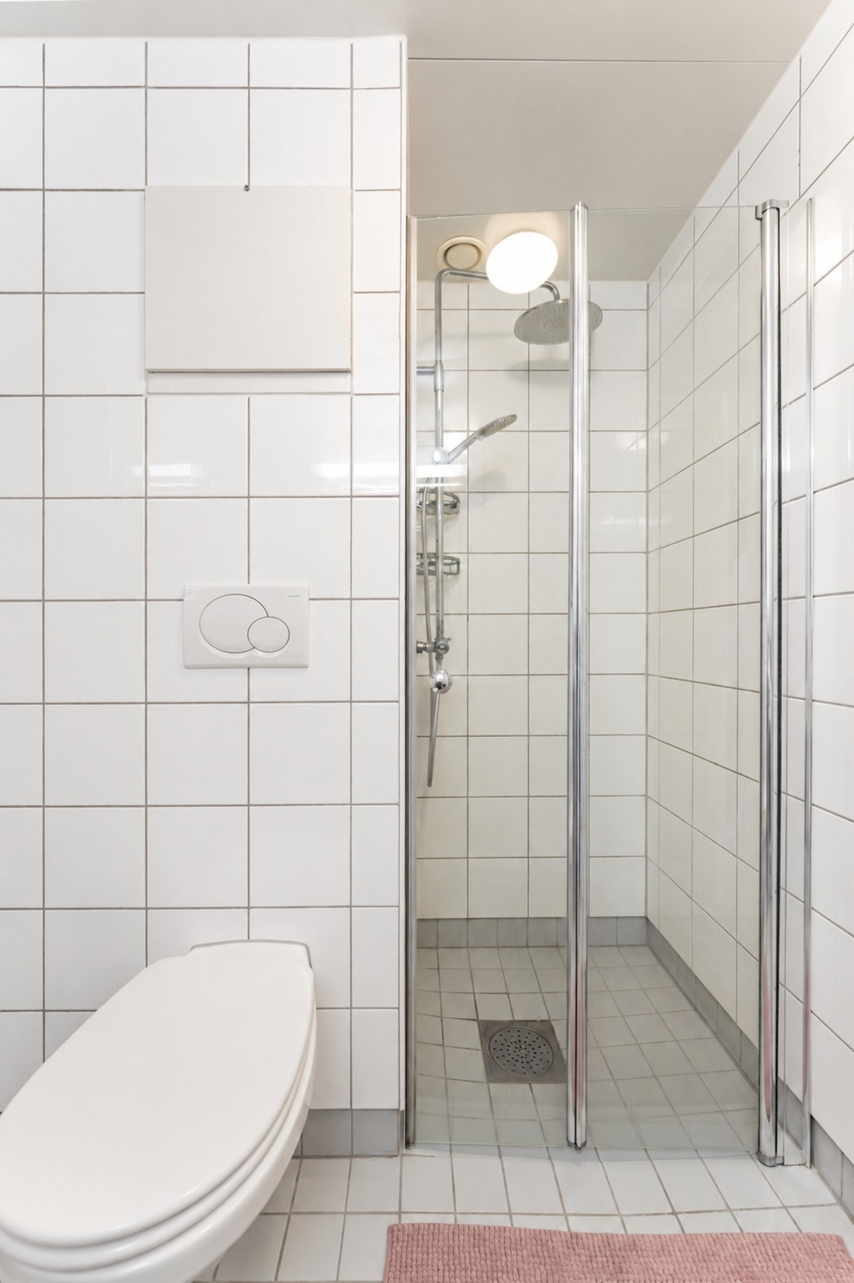 Badet er innredet med nedsenket dusjnisje med foldedør i herdet glass, vegghengt toalett, servantseksjon med skuffer og speil. Galleribilde