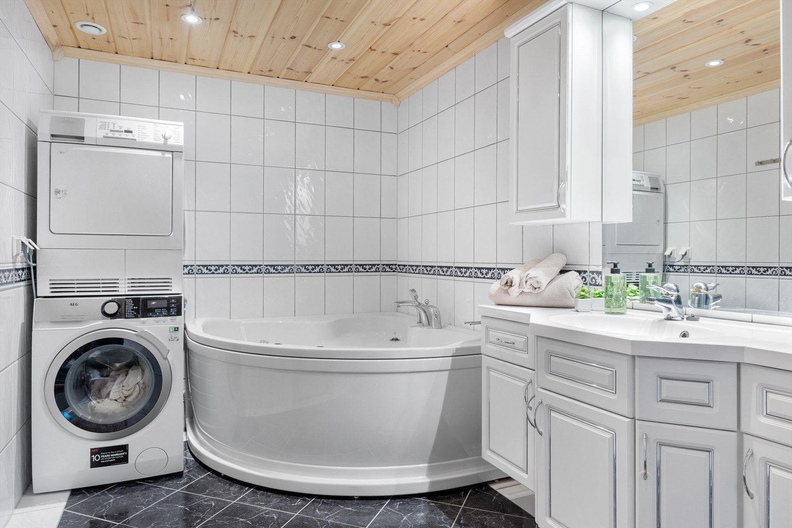 Badet er helfliset og fremstår nøytralt og moderne. Det innredet med toalett, dusj, hjørnebadekart og servant med møblement. Her er det også opplegg for vaskemasking, svært praktisk på hytten. Det er selvsagt varmekabler i gulvet. Galleribilde