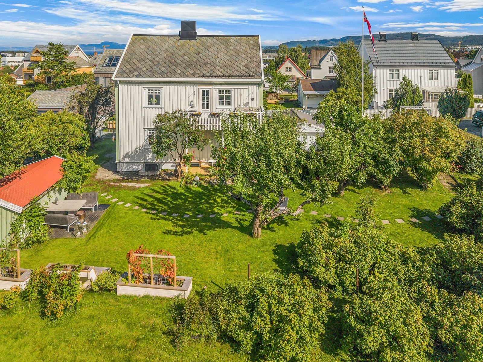 Fra luften får man et godt inntrykk av den romslige tomten og den flotte hagen som omkranser boligen. Galleribilde
