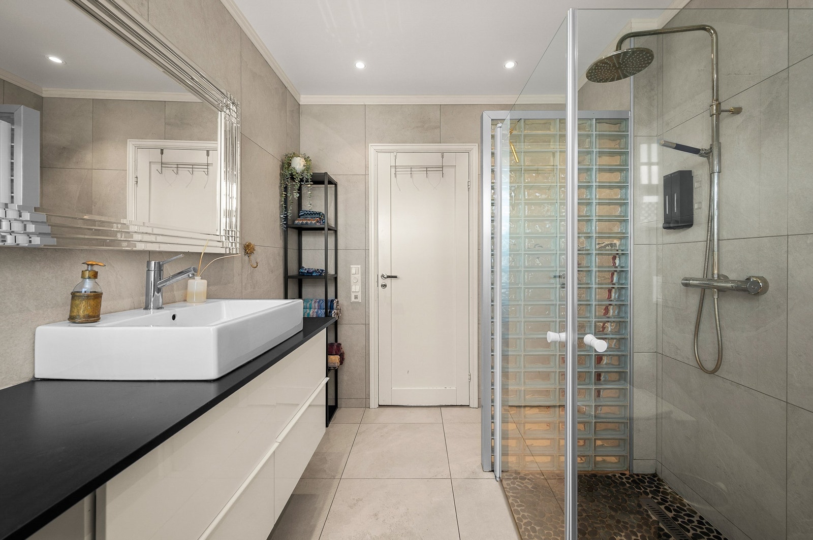 Badet har en romslig dusjsone med både hånd- og takdusj, samt moderne og tidløse flisvalg. Galleribilde