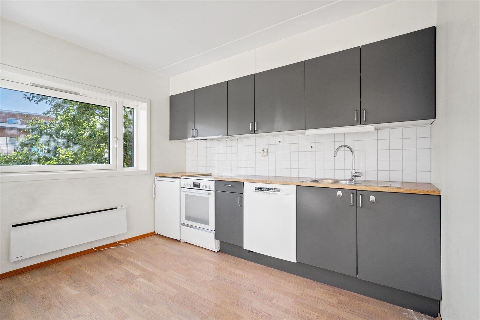 Langs den ene veggen er det montert et kjøkken i mørk utførelse med glatte fronter og laminat benkeplate med kum. Galleribilde