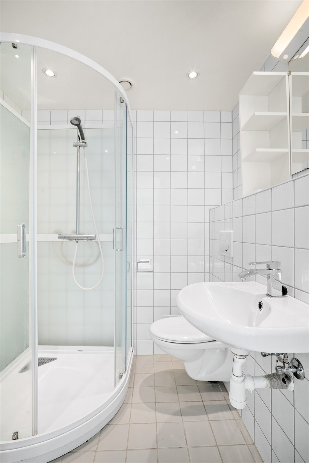 Badet har servant med speil over, vegghengt toalett og dusjkabinett med garnityr. Galleribilde